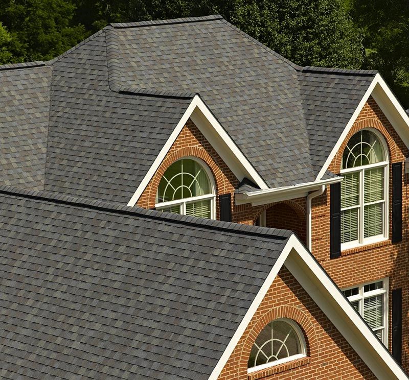 Brick house with dark grey shingle roof, white trim, and arched windows.