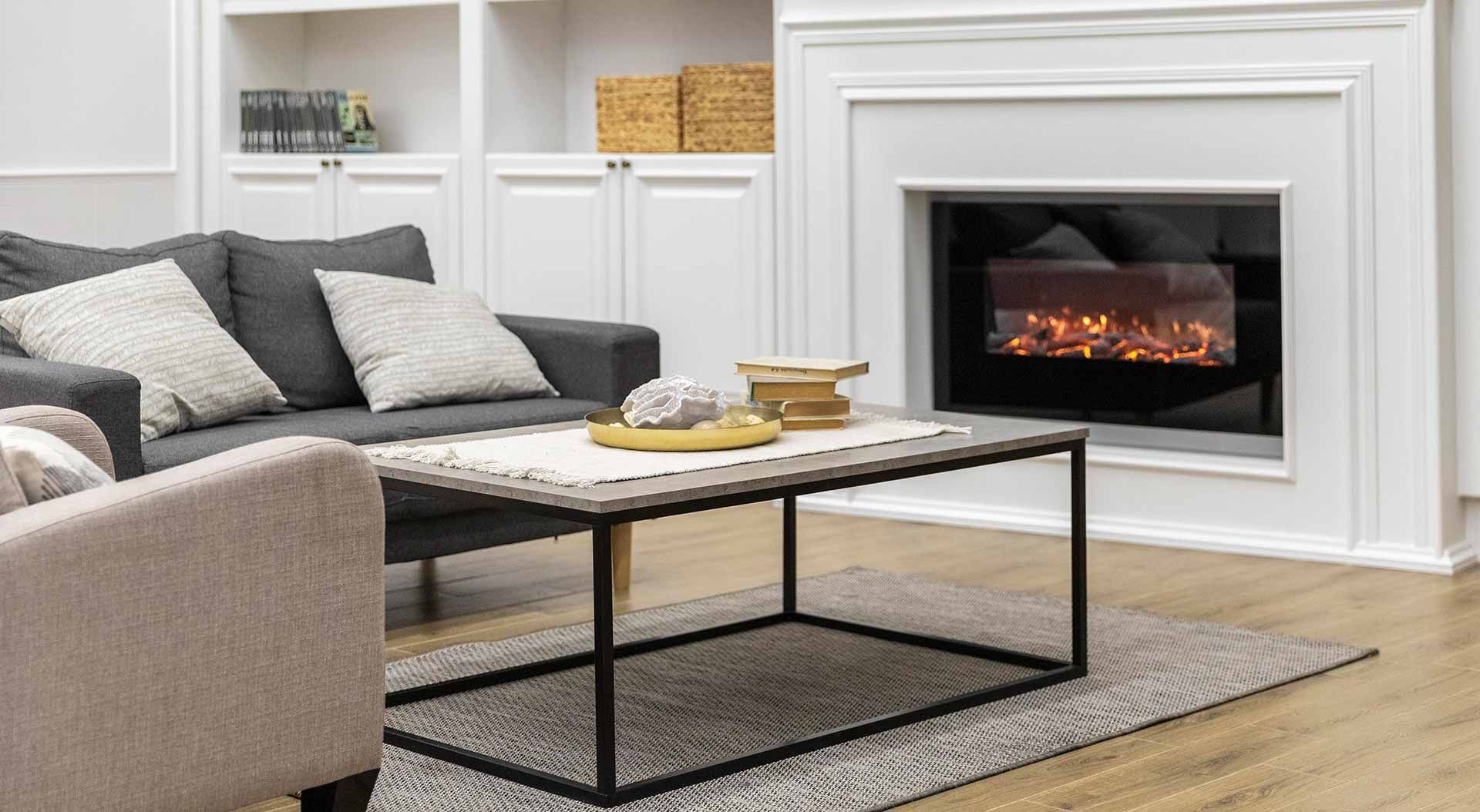 Cozy living room with a dark gray sofa, fireplace, coffee table, and area rug.
