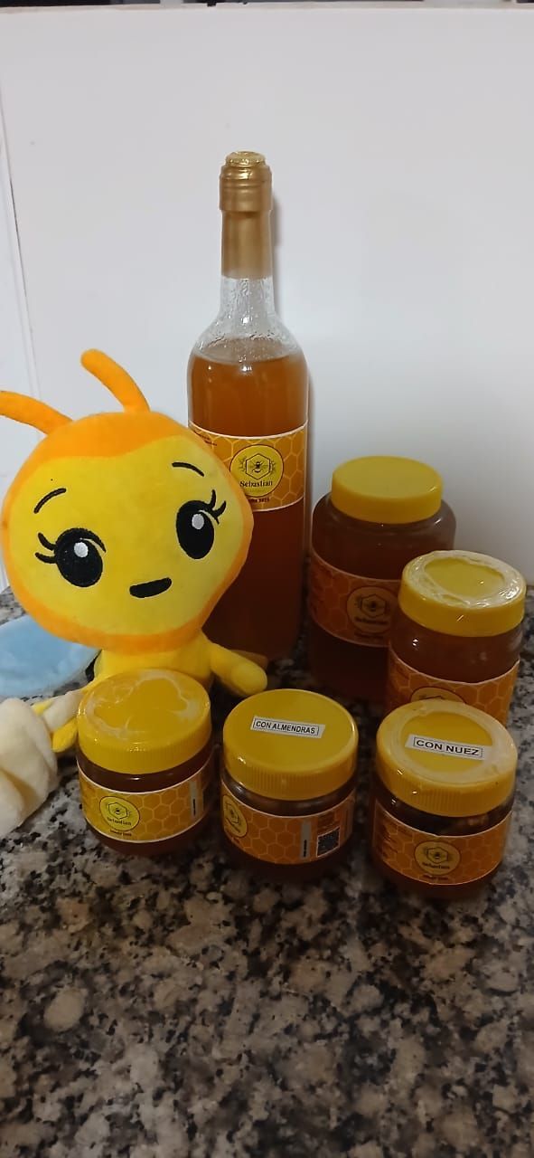 Un peluche amarillo junto a tarros de miel y una botella sobre una encimera moteada.