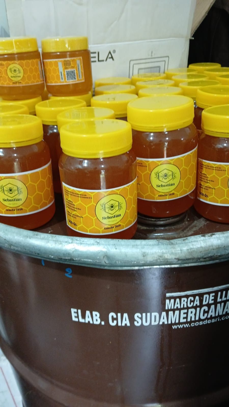 Muchos frascos de salsa roja con tapas amarillas apilados en un recipiente de metal.