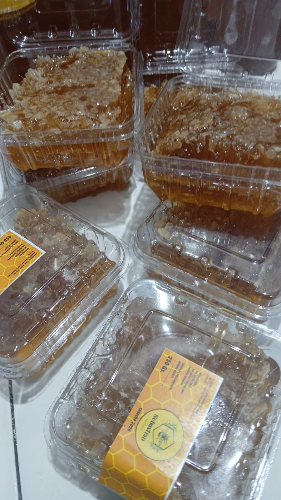 Envases de plástico transparente con forma de panal de abeja dorado apilados sobre una superficie.