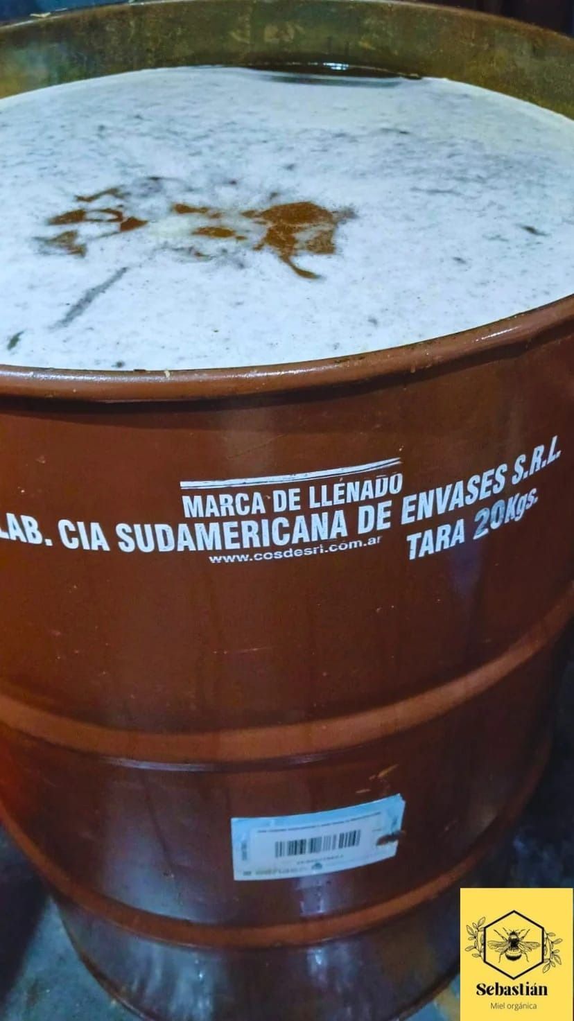 Tambor de metal oxidado con polvo blanco en la parte superior y etiqueta con texto en español en el lateral.