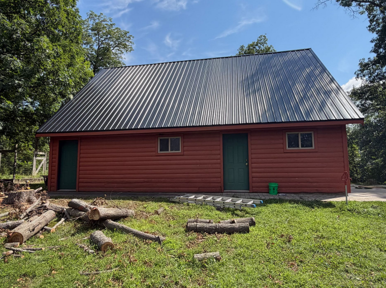 Red log building exterior with metal roofing in Lansing, IA.