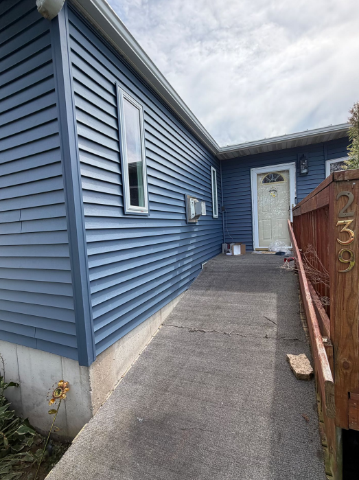 Home entryway and wheelchair ramp with blue siding in Lansing, IA.