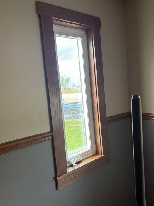 New window installation with wooden trim in Lansing, IA.