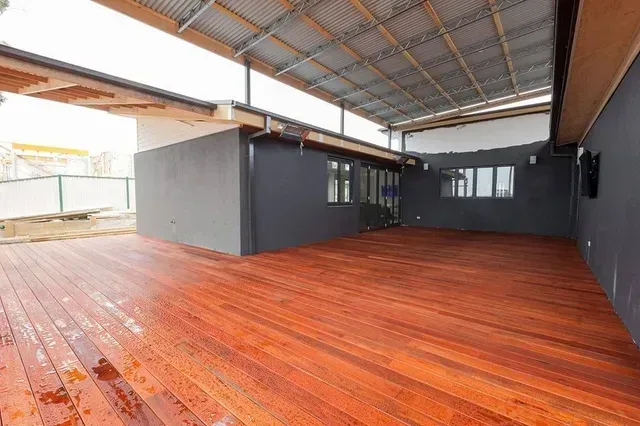 A Large Empty Room With a Wooden Floor and a Roof — Evoke Building Group In Maryborough, VIC