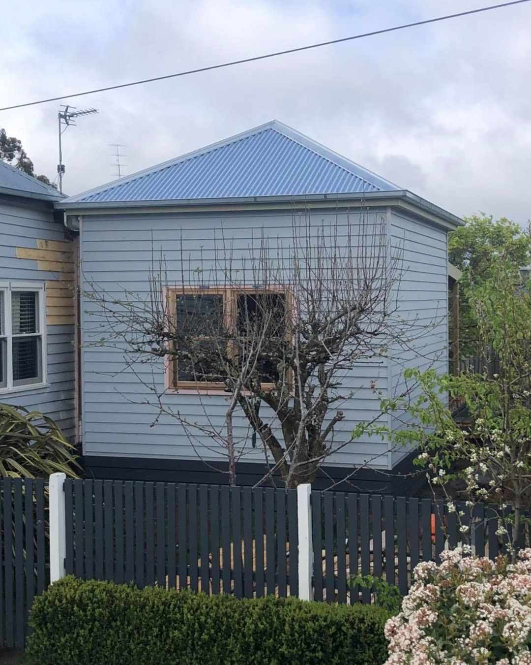 A Small House With a Blue Roof and a Black Fence — Evoke Building Group In Ballarat Central, VIC