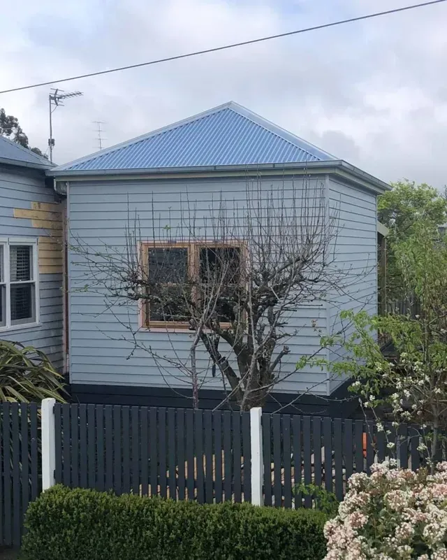 A Small House With a Blue Roof and a Tree in Front of It — Evoke Building Group In Ballarat Central, VIC