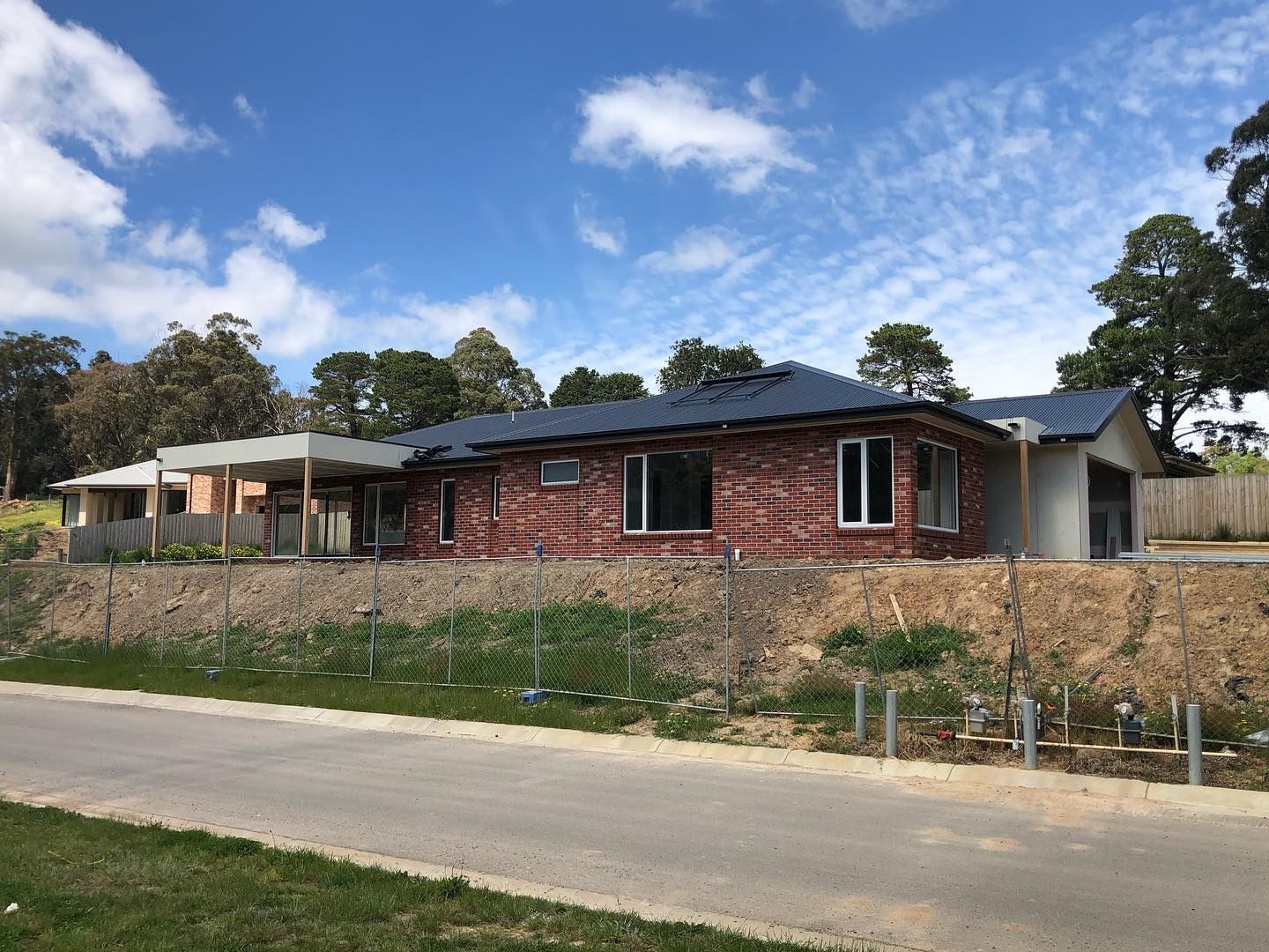 A Brick House is Being Built on a Hill Next to a Road — Evoke Building Group In Ballarat Central, VIC