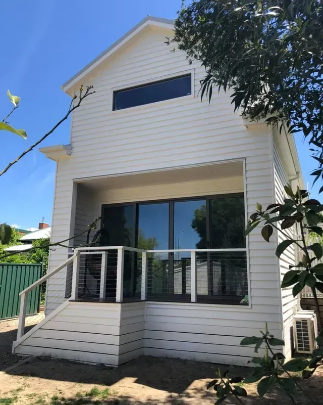 A Small White House With a Balcony and Stairs — Evoke Building Group In Maryborough, VIC
