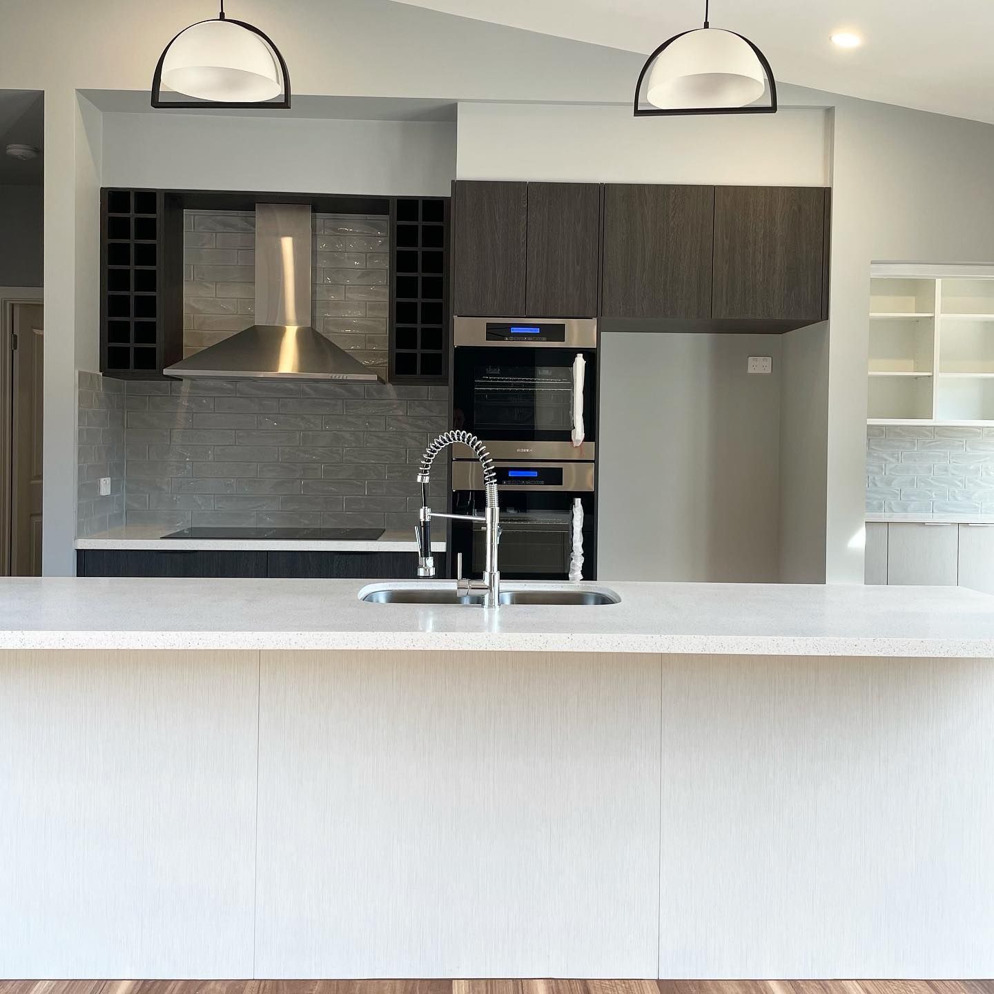 Modern kitchen with island, dark cabinets, stainless appliances, and pendant lights.