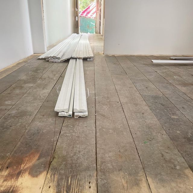 A Stack of White Trim is Sitting on a Wooden Floor — Evoke Building Group In Ballarat Central, VIC