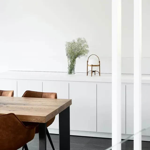 A Dining Room With a Wooden Table and Chairs and a Vase of Flowers on the Counter — Evoke Building Group In Geelong, VIC