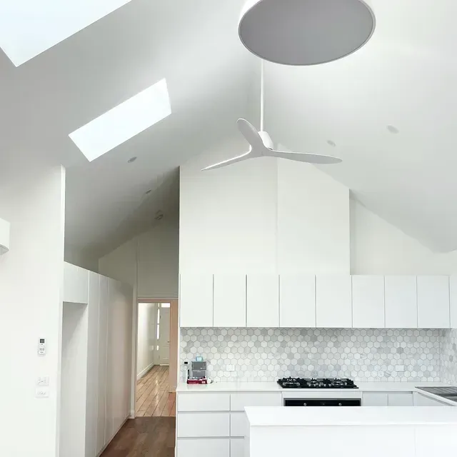 A Kitchen With White Cabinets and a Ceiling Fan — Evoke Building Group In Ballarat, VIC