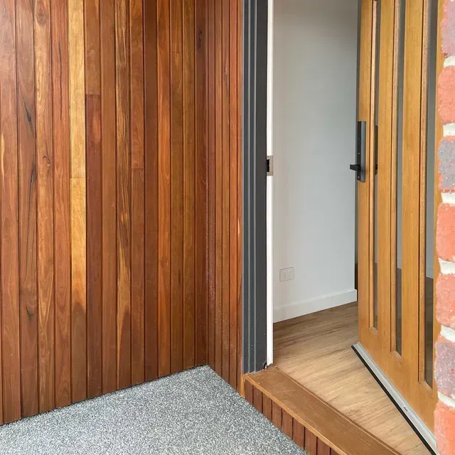 A Wooden Door is Open to a Room With a Brick Wall — Evoke Building Group In Maryborough, VIC