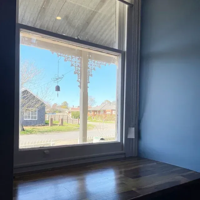 A Window With a View of a House and a Bell Hanging From the Ceiling — Evoke Building Group In Daylesford, VIC