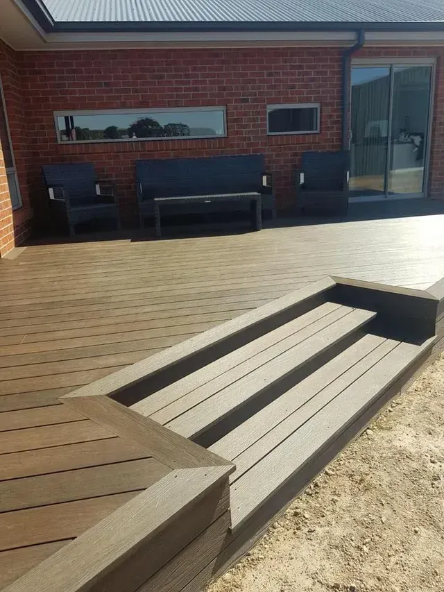 A Wooden Deck With Stairs and a Bench in Front of a Brick House — Evoke Building Group In Ballarat, VIC