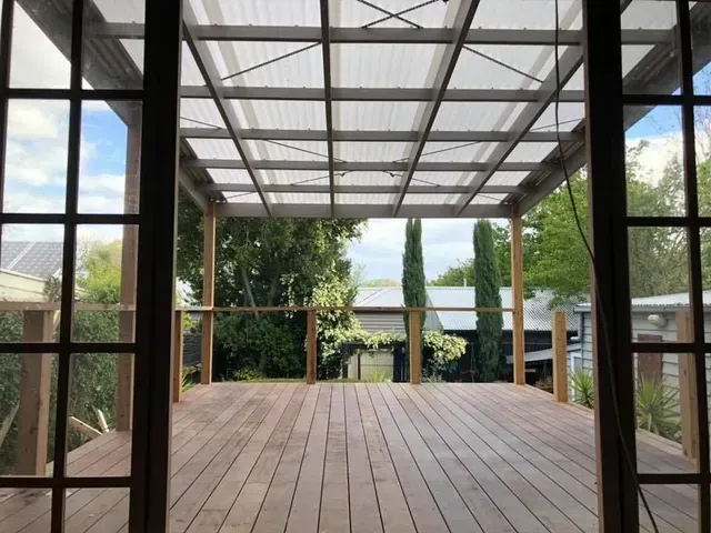 A wooden deck with a clear roof and sliding glass doors — Evoke Building Group In Bendigo, VIC