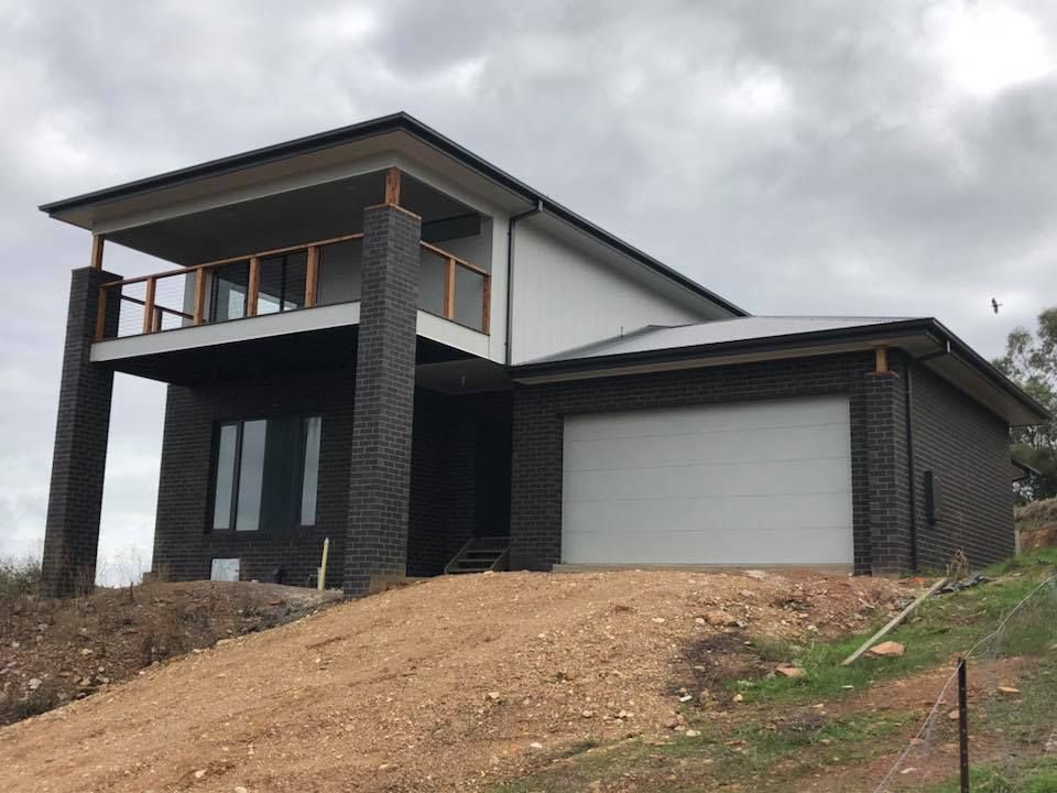 A Large House is Sitting on Top of a Dirt Hill — Evoke Building Group In Ballarat Central, VIC