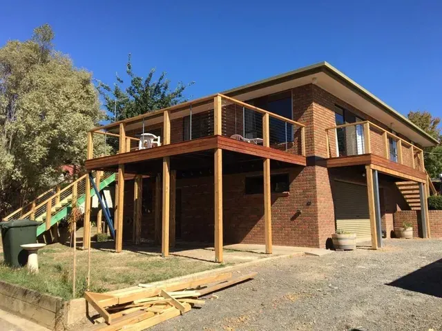 A Brick House With a Wooden Deck and Stairs — Evoke Building Group In Maryborough, VIC