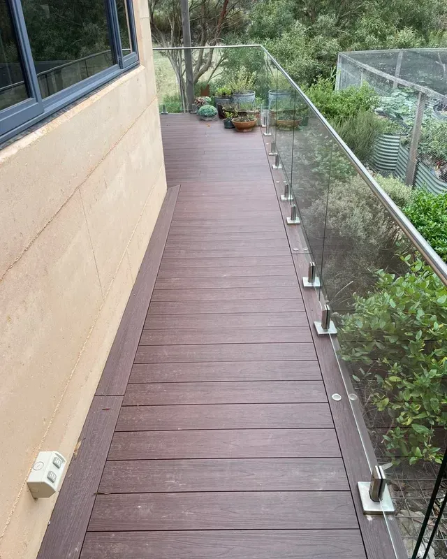 A Wooden Deck With a Glass Railing Next to a Building — Evoke Building Group In Bendigo, VIC