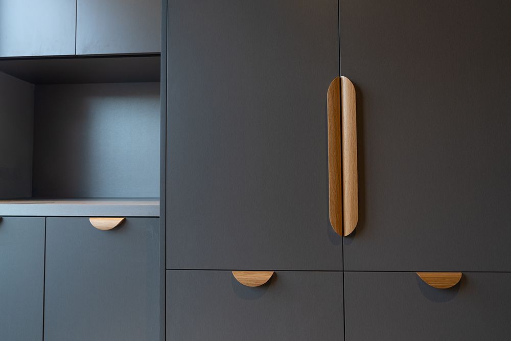 Gray cabinets with wooden handles in a modern kitchen.