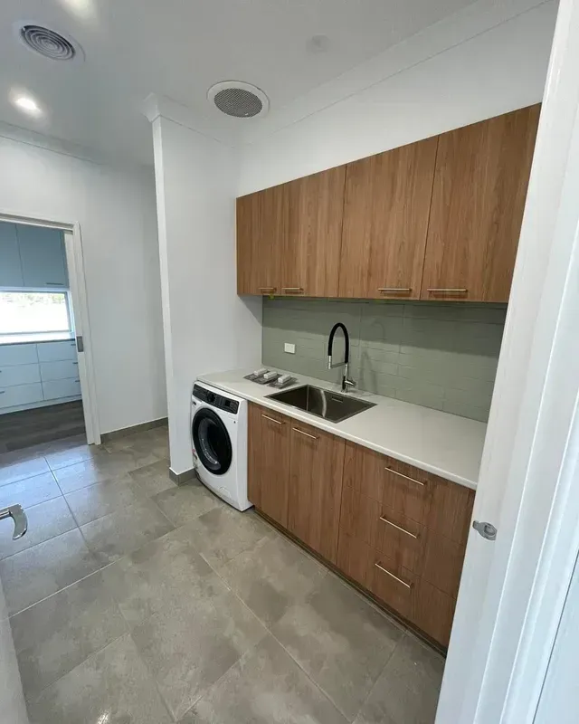 A Kitchen With Wooden Cabinets, a Washer and Dryer, and a Sink— Evoke Building Group In Maryborough, VIC
