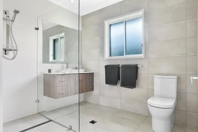 A Bathroom With a Toilet, Sink, Mirror and Walk in Shower — Evoke Building Group In Ballarat Central, VIC
