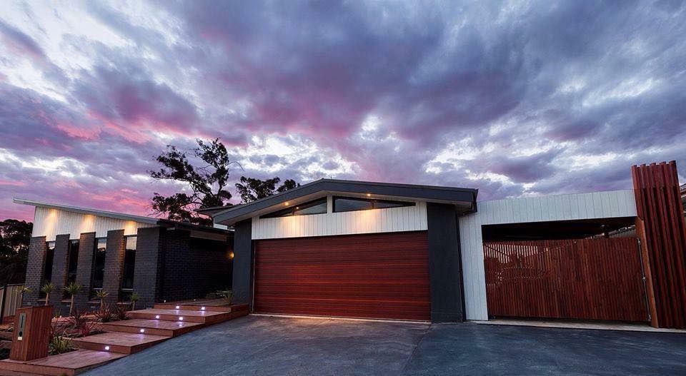 A Modern House With a Red Garage Door and a Purple Sky in the Background — Evoke Building Group In Ballarat Central, VIC