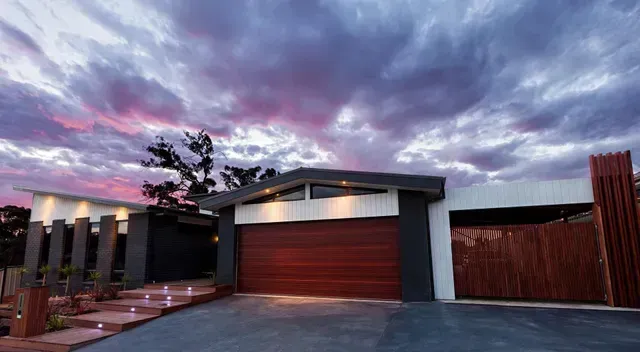 Modern home exterior with a brown garage door, steps, and a dramatic sky.