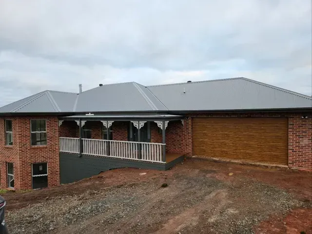 A Large Brick House With a Garage and Porch — Evoke Building Group In Daylesford, VIC