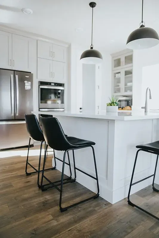 A Kitchen With White Cabinets, Black Chairs, a Refrigerator, and a Sink — Evoke Building Group In Ballarat Central, VIC