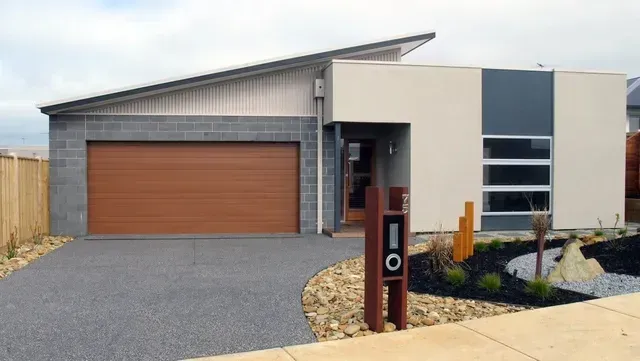 A Modern House With a Brown Garage Door and a Mailbox in Front of It — Evoke Building Group In Ballarat Central, VIC