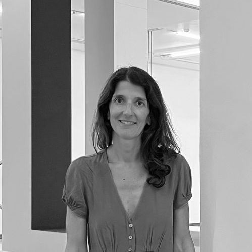 Una mujer está parada frente a una pared en una foto en blanco y negro.