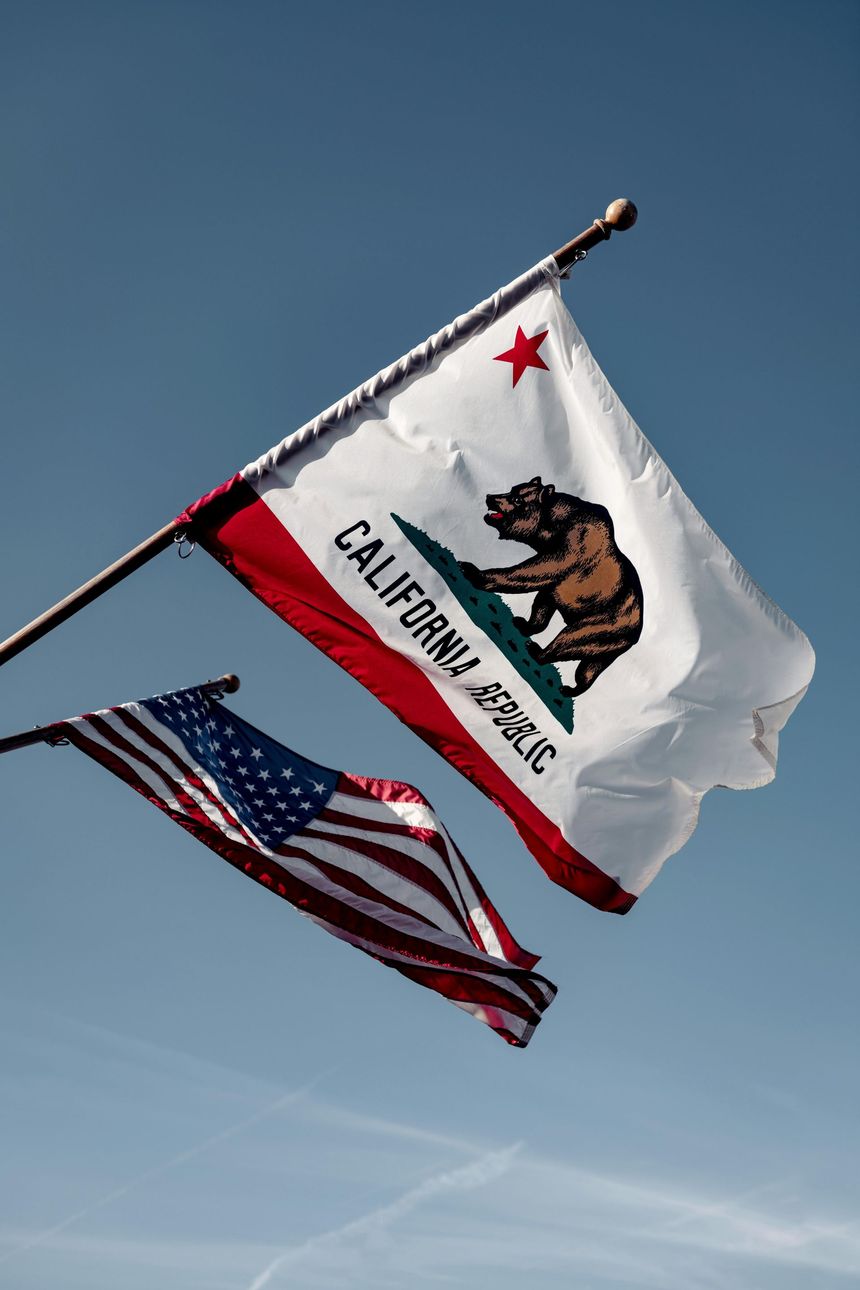 California state flag and U.S. flag waving against a blue sky
