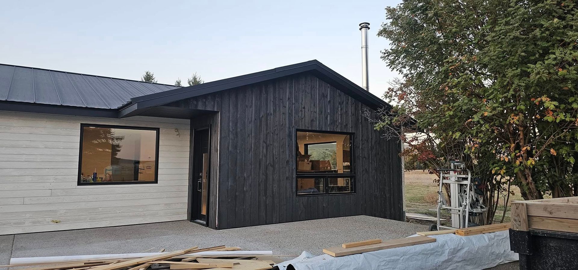 A modern, split-design home with one side featuring white horizontal planks and the other side charred black vertical wood.