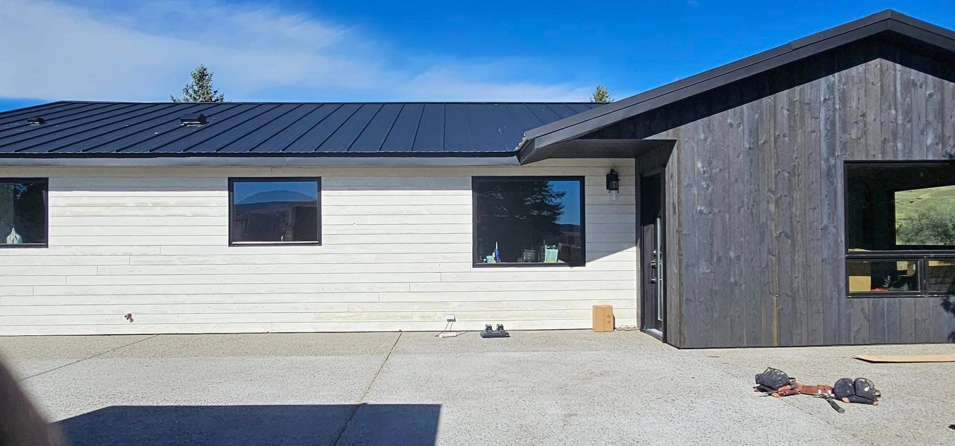 A single-story home featuring a contrast between white horizontal wood siding and dark vertical charred wood siding.
