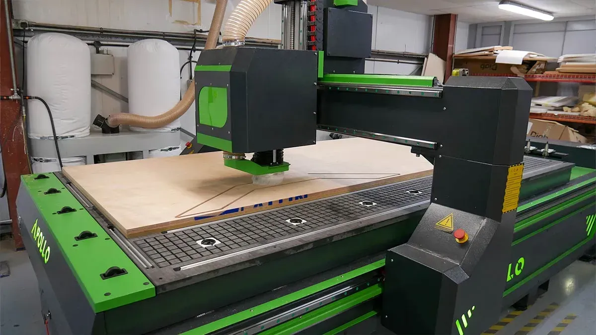 Green-and-black CNC router cutting a sheet of wood
