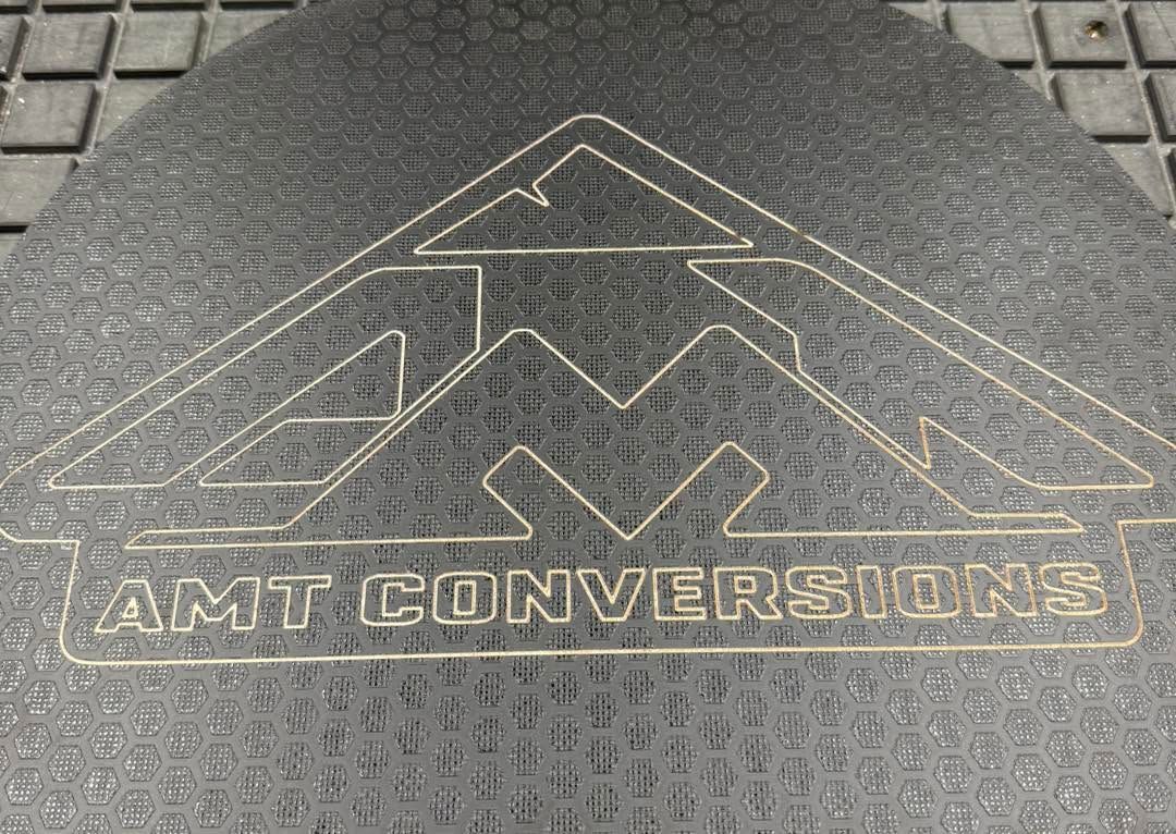 Black textured mat with mountain logo and the words “JUST CONVERSIONS” embossed on it