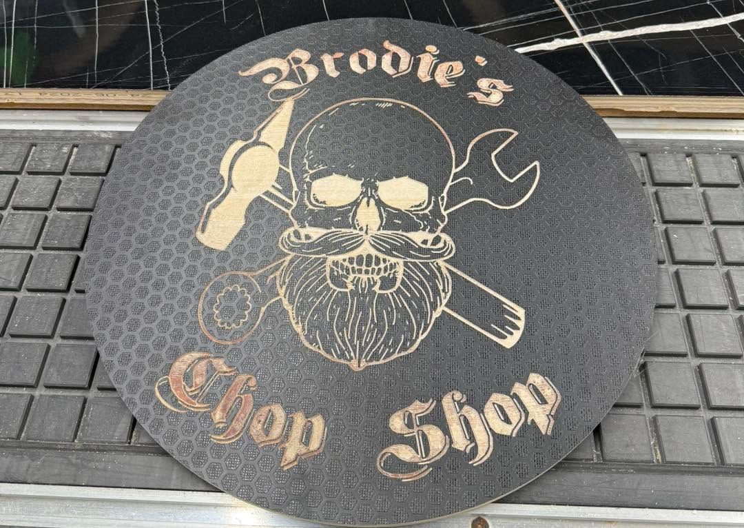 Brodie’s Chop Shop logo on a black circular mat with skull, knife, and pipe design