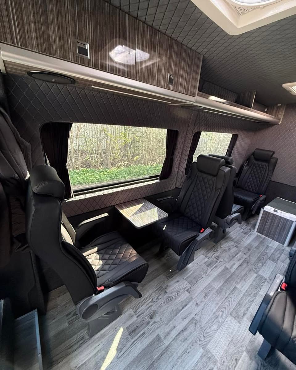 Spacious golf van interior featuring scotseat seats, wood accents, and large side windows overlooking trees.