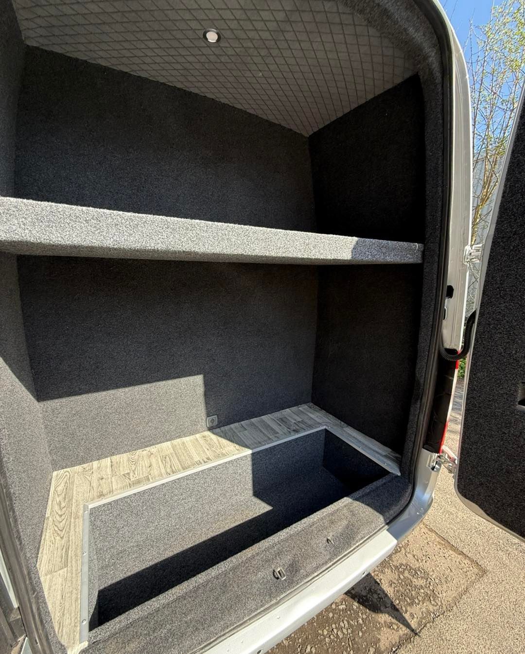 Open storage compartment in the back of a golf van, showing built-in shelves and carpeted interior.