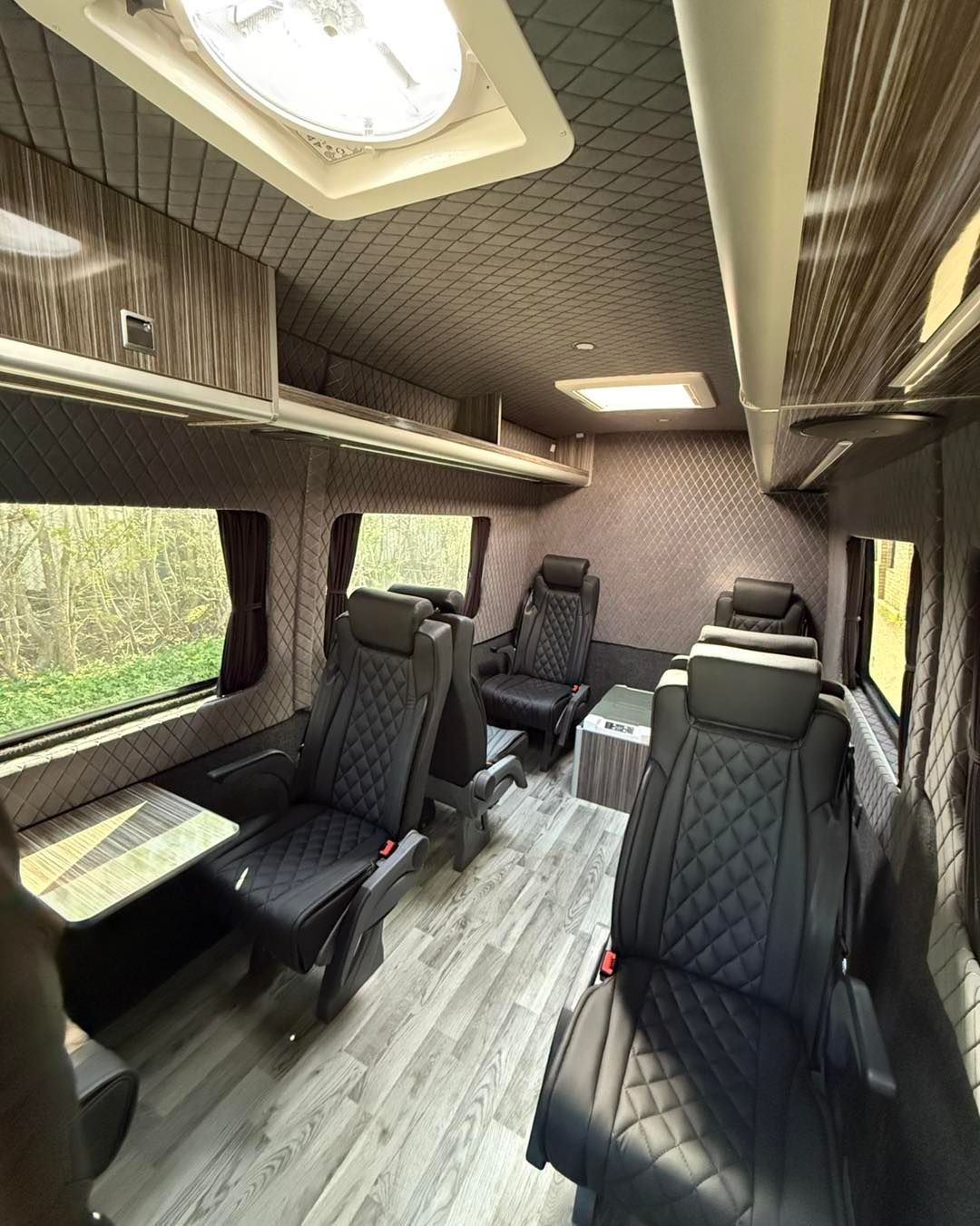 Spacious golf van interior featuring scotseat seats, wood accents, large side windows and skylights overlooking trees.