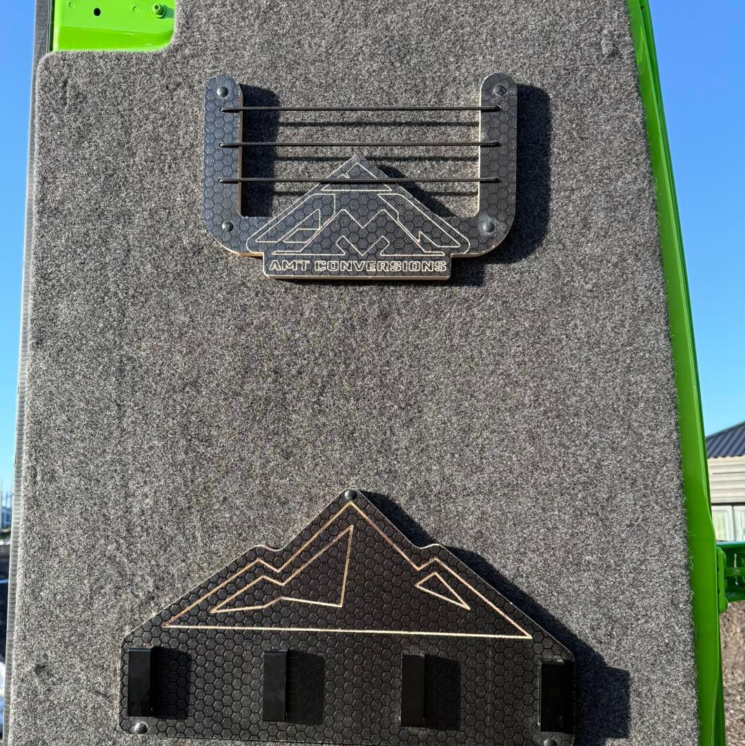 Close-up of two black climbing holds mounted on a gray wall, one shaped like a U and one like a mountain.
