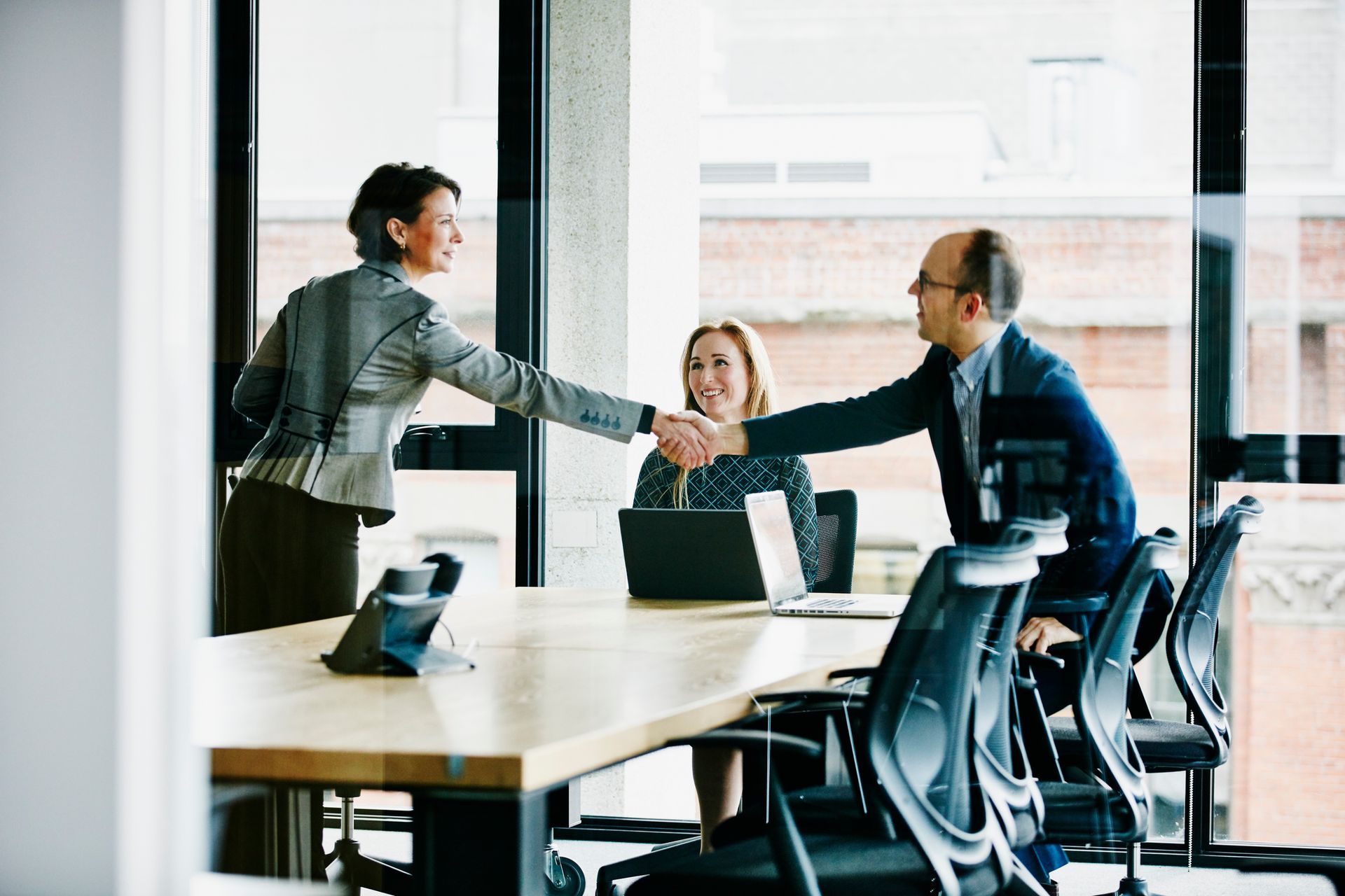 A man and a woman are shaking hands in a conference room.