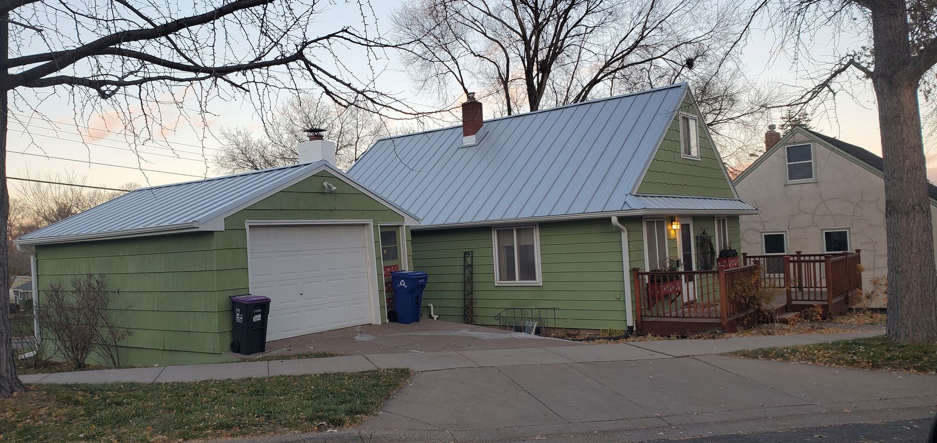 A green house with a white roof and a garage