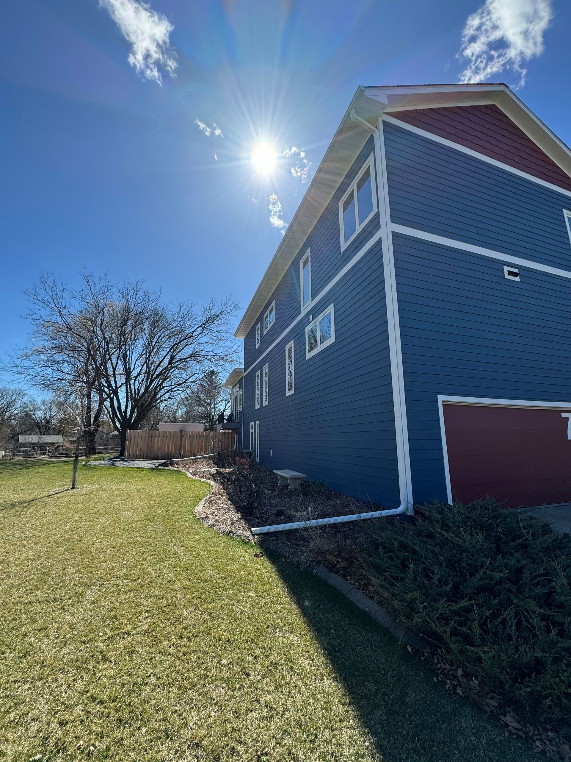 A large blue house with a red roof is sitting on top of a lush green lawn.