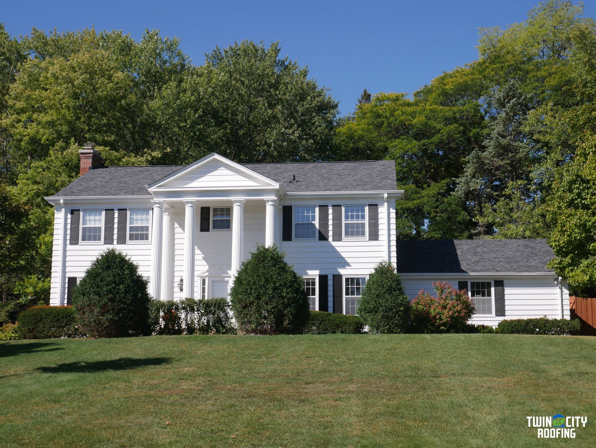 A large white house sits on top of a lush green hillside