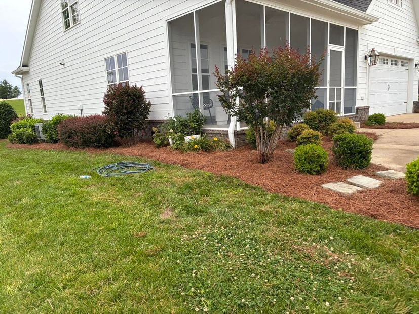 White house with screened porch, landscaped front yard, red mulch beds, and a concrete walkway