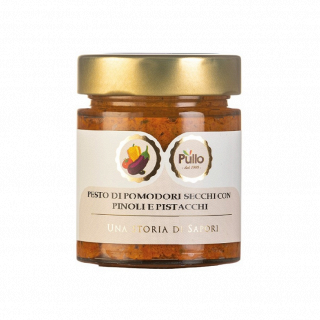 Glass jar of tomato pesto with gold lid and label reading “Pesto di pomodori secchi con pinoli e pistacchi”